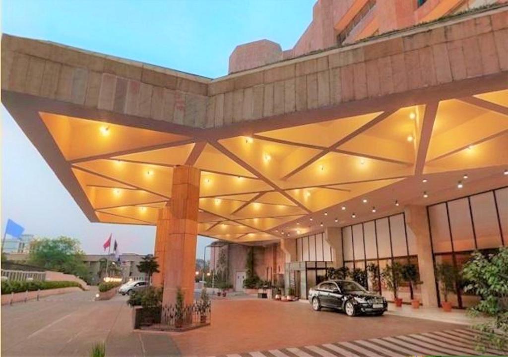 a building with a car parked in a parking lot at Hotel Samrat, New Delhi in New Delhi