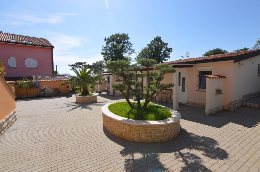 un patio con un pequeño árbol en un círculo de piedra en Apartmani Dekovic Materada, en Poreč