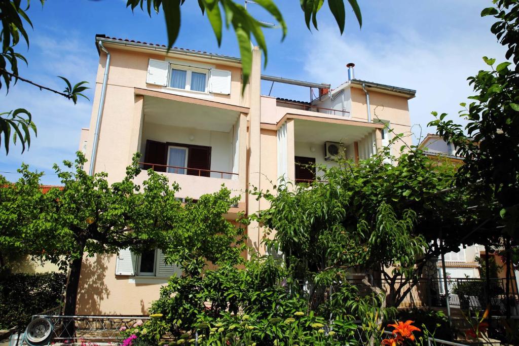 a pink building with trees in front of it at Apartments & Rooms Samohod in Vodice