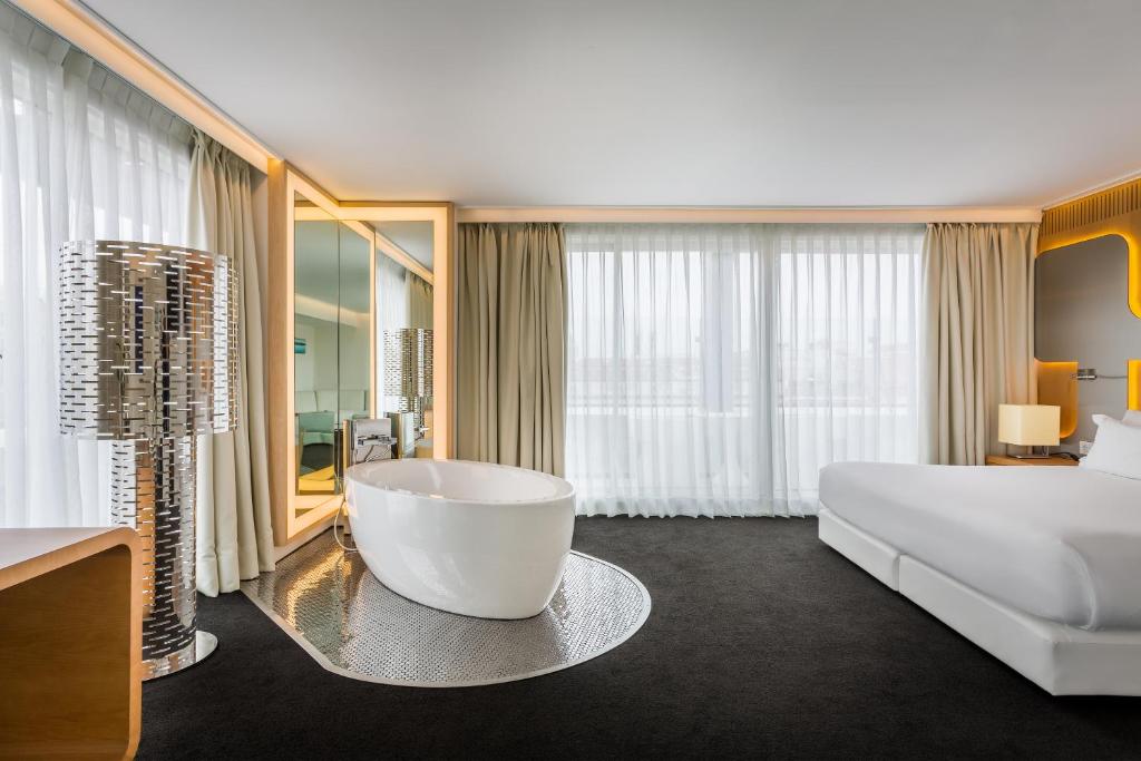 a hotel room with a large bed and a large tub at Room Mate Oscar, Madrid in Madrid