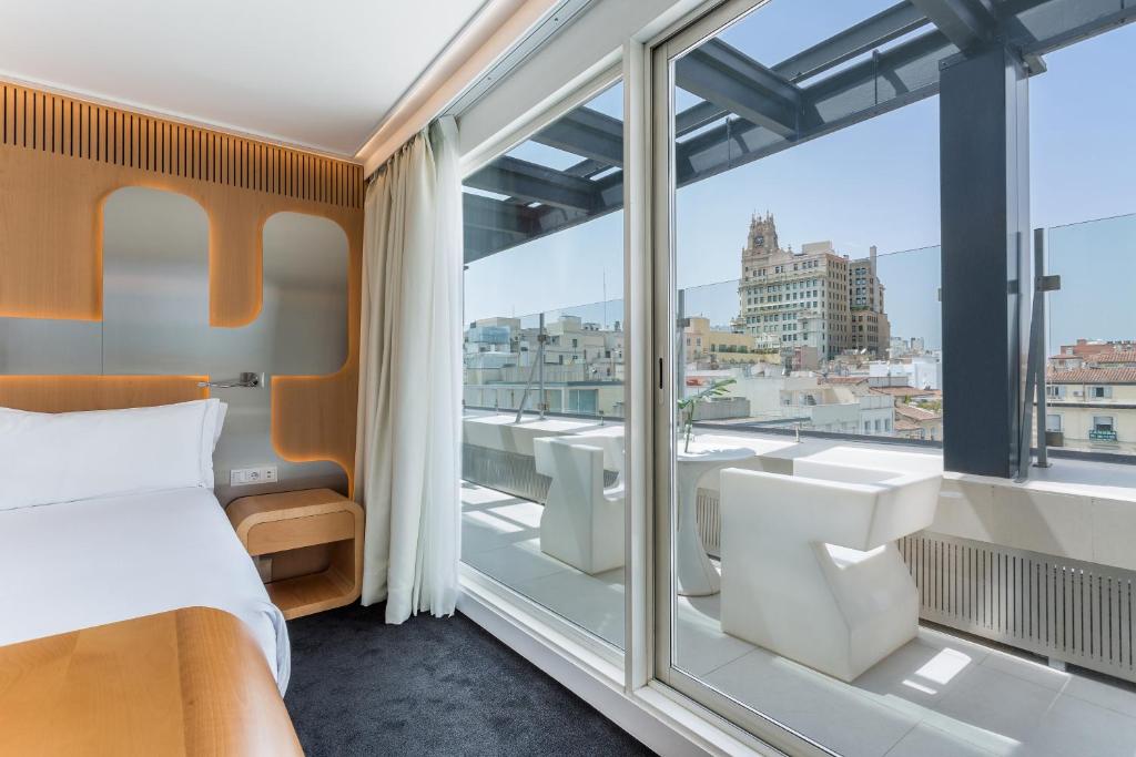 a bedroom with a bed and a large window at Room Mate Oscar, Madrid in Madrid