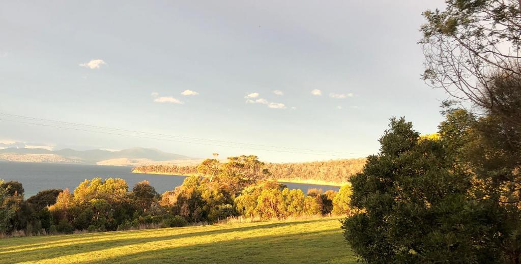 a grassy field with a lake in the background at Convict Beach Coastal Retreat in Saltwater River