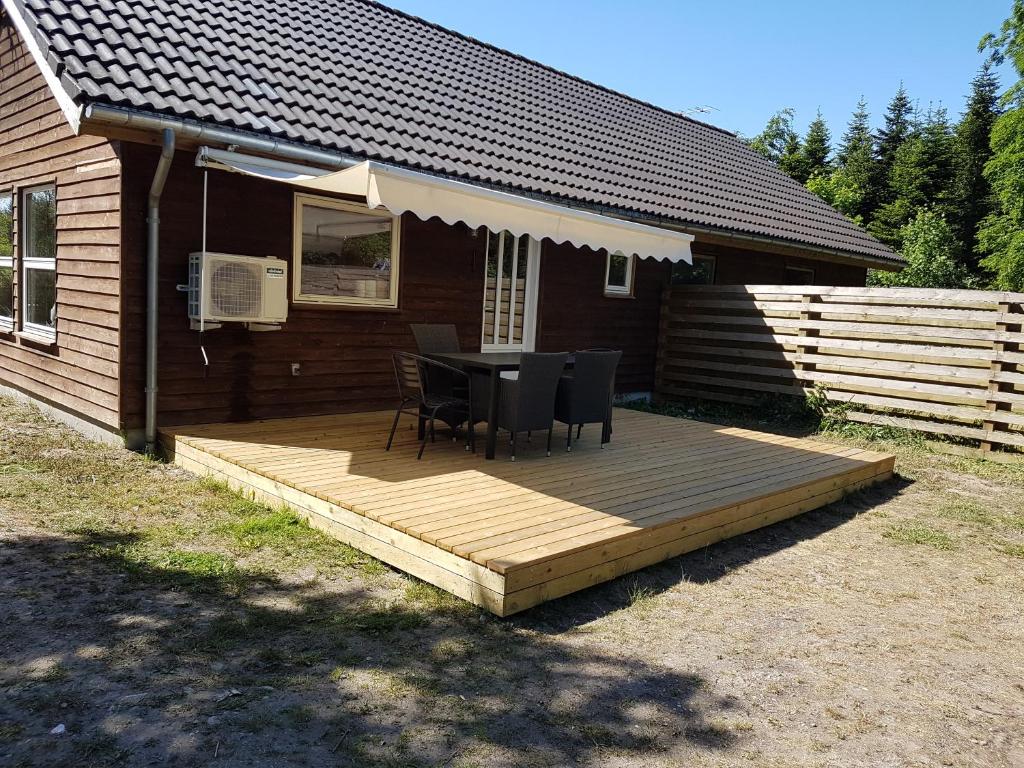 een houten terras met een tafel en stoelen voor een huis bij Jagthytten in Randbøldal