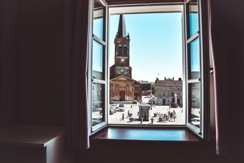 een open raam met uitzicht op een klokkentoren bij Hôtel L'etoile De Marie in Rocroi