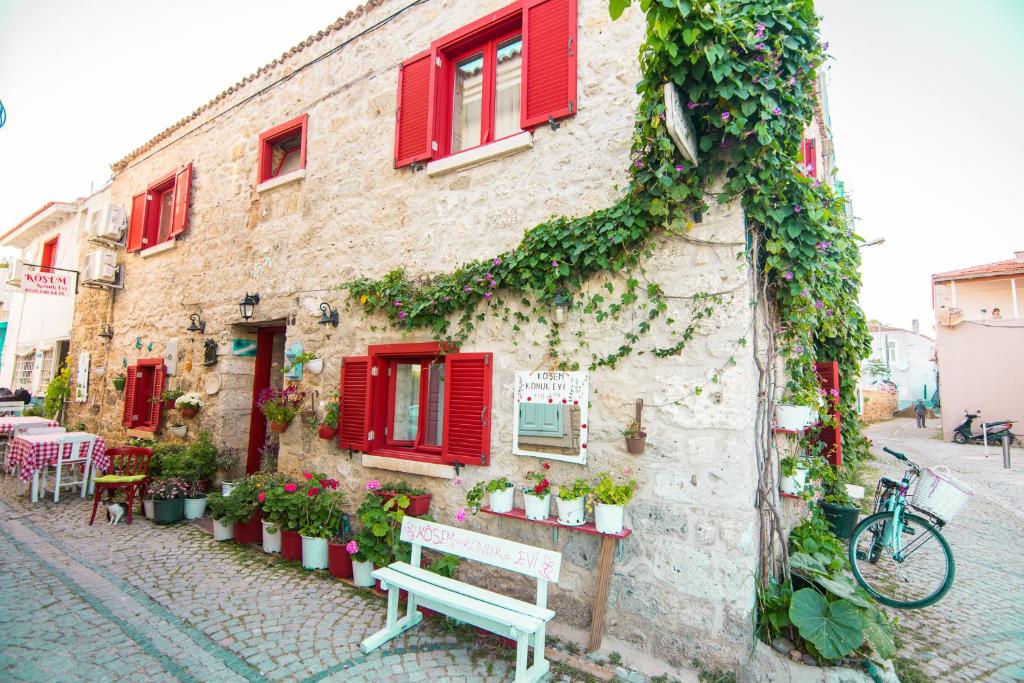 a stone building with red windows and a bench at Köşem Konukevi in Alacati
