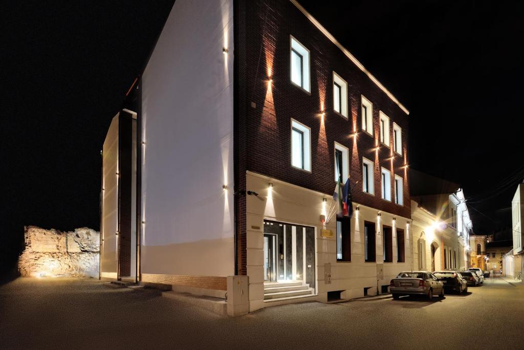un bâtiment avec une voiture garée devant lui la nuit dans l'établissement Dominus Residence, à Cluj-Napoca