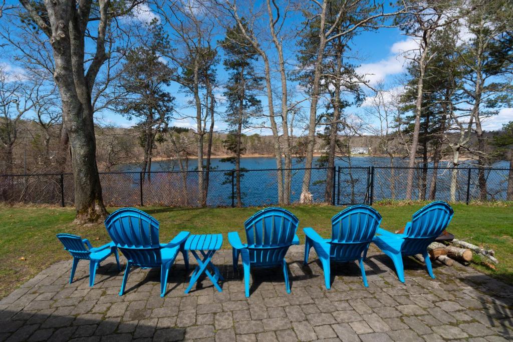 a group of four blue chairs sitting in front of a lake at Weeks Pond Charmer in Forestdale