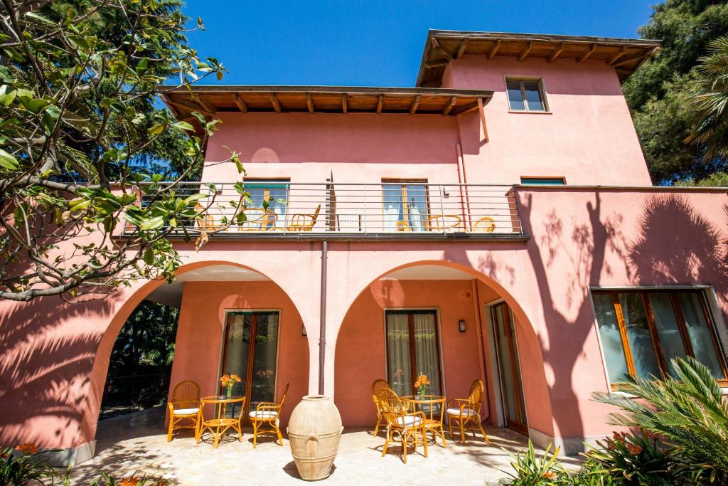 Villa Rosa Sorrento في سورينتو: منزل وردي مع شرفة وطاولات وكراسي