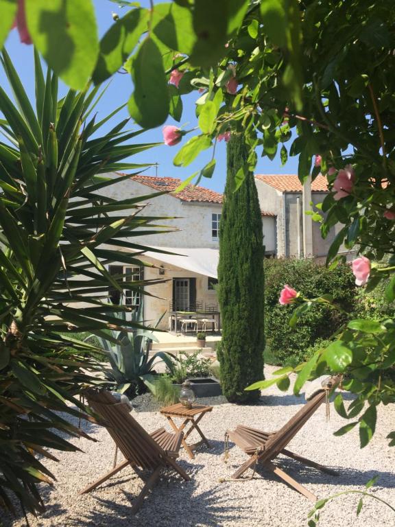 deux chaises assises sur le sable devant un bâtiment dans l'établissement La Maison du Baloir, à Thairé