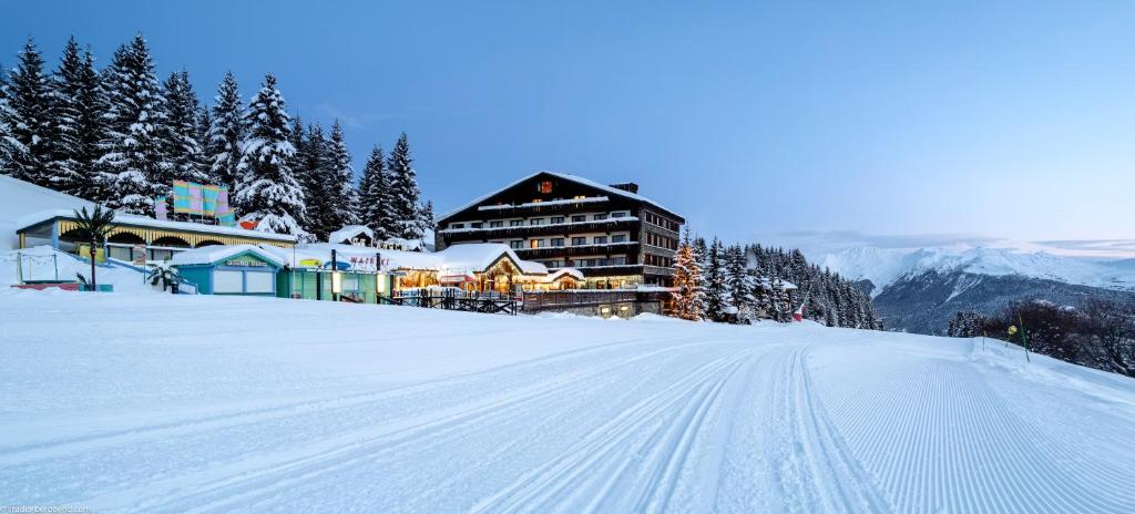a snow covered slope with a building on a mountain at Hôtel Courcheneige in Courchevel