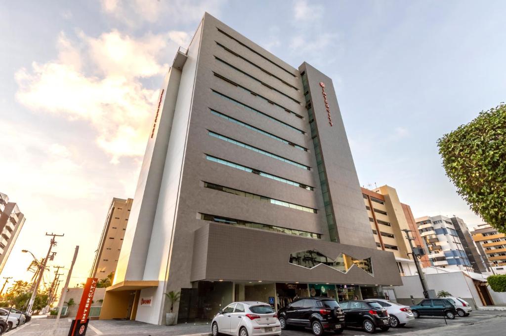 a building with cars parked in front of it at Intercity Maceio in Maceió