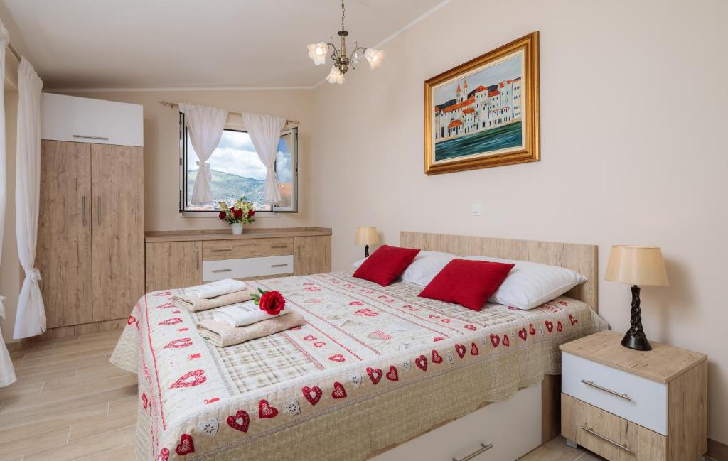 een slaapkamer met een groot bed met rode kussens bij Apartmani Oaza in Trogir