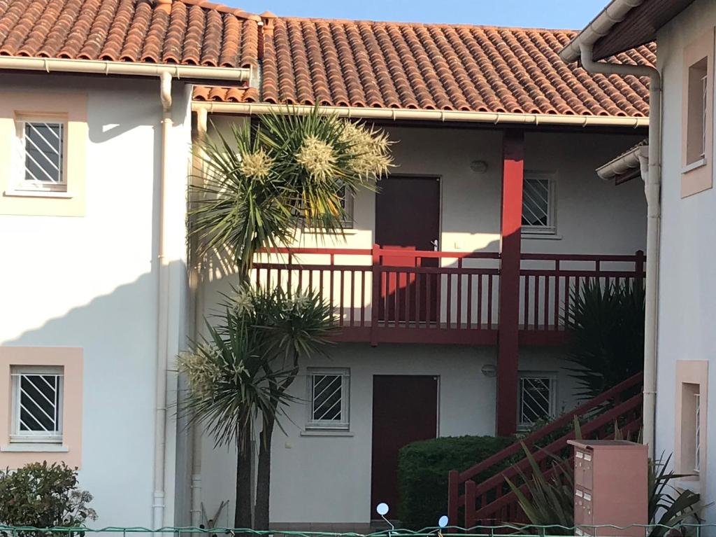 une maison dotée d'un balcon avec des palmiers en face de celle-ci dans l'établissement Clos ETCHBERRI, à Bidart