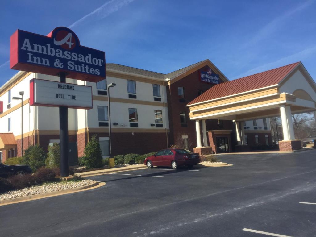 un'auto parcheggiata di fronte a una locanda e a delle suite di Ambassador Inn & Suites a Tuscaloosa