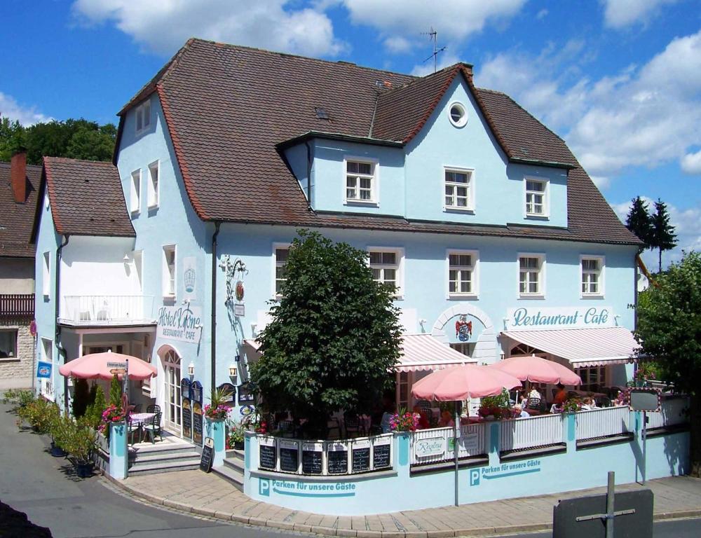 ein weißes Gebäude mit rosa Sonnenschirmen davor in der Unterkunft Hotel Krone in Gößweinstein