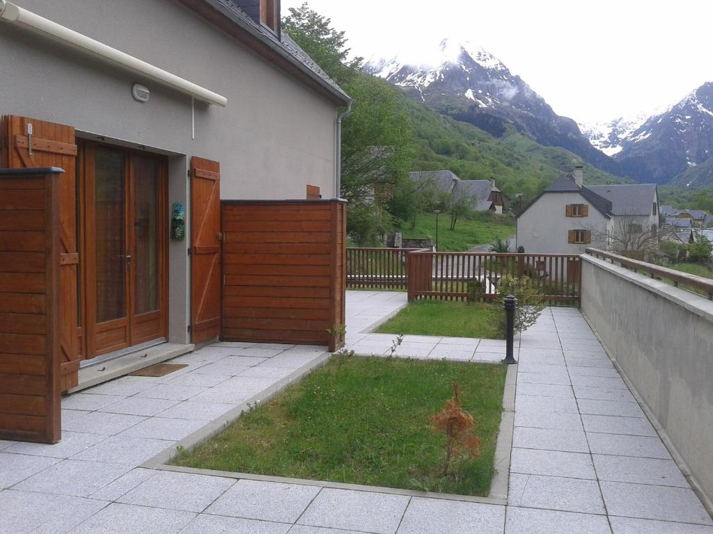 a house with a gate and a yard with mountains at Granges de Trescazes in Loudenvielle
