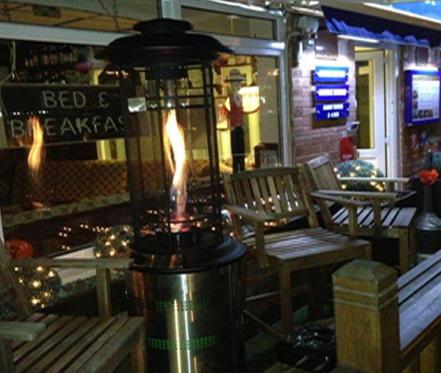 a restaurant with a heater in front of a table and chairs at Clifton Court Hotel in Blackpool