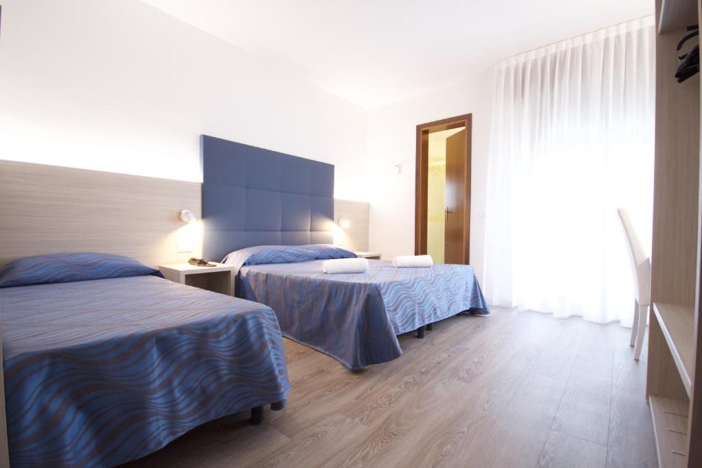una camera d'albergo con due letti e uno specchio di Hotel Serenella a Lido di Jesolo