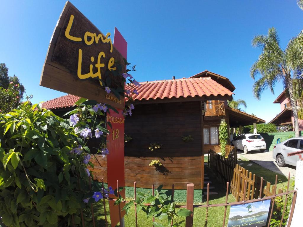 un panneau devant une maison en rondins dans l'établissement Long Life Campeche-Pousada, à Florianópolis