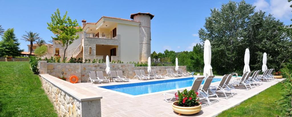 een villa met een zwembad en stoelen en een huis bij Rahona Villas in Siviri