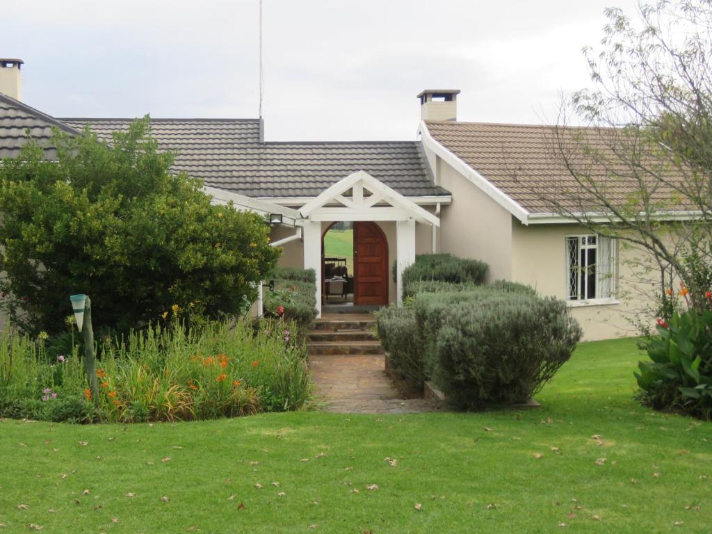 una casa bianca con una porta marrone e un cortile di Dunroamin Bed and Breakfast a Mooi Rivier