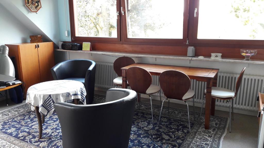 Cette chambre comprend une table, des chaises et des fenêtres. dans l'établissement Im Baumhaus, à Roth