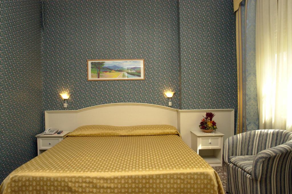 a bedroom with a bed and two chairs at Hotel Vittoriano in Turin