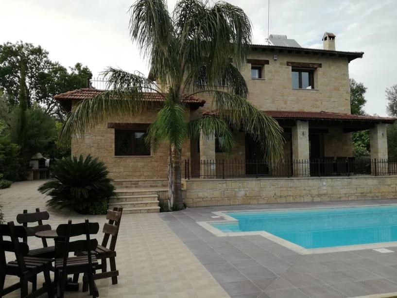 a house with a palm tree and a swimming pool at Valencia Grove Villa in Miliou