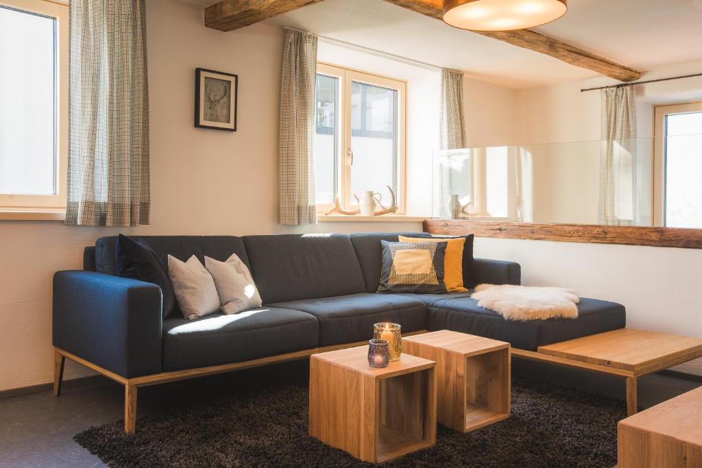 uma sala de estar com um sofá azul e duas mesas em Villa Mulin im Sommer inklusive Bergbahnticket Super Sommer Card em Ladis