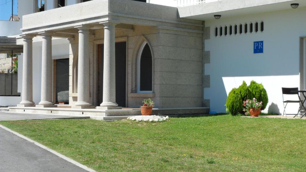 a building with columns and grass in front of it at Hostal La Paz in Vista Alegre