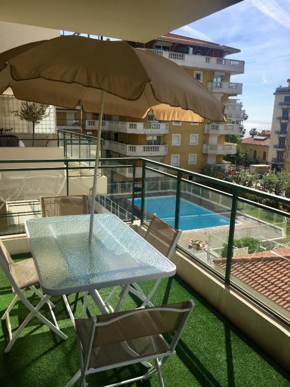 une table et des chaises sur un balcon avec un parasol dans l'établissement Palais des Domes Gloria, à Nice