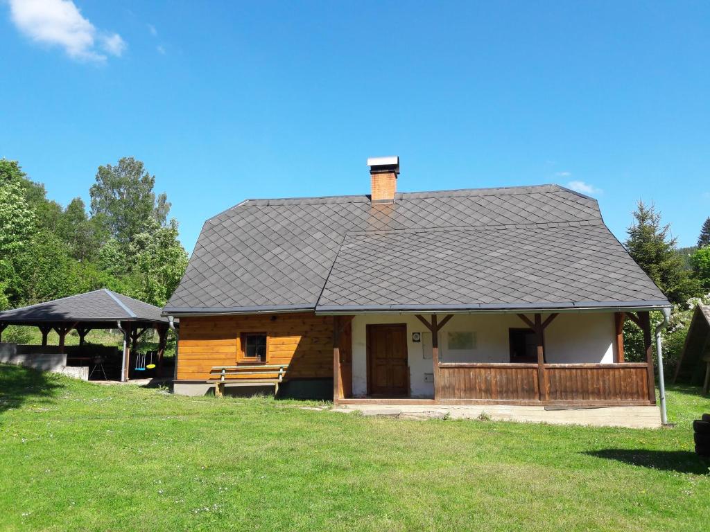 a log cabin with a roof on a grass field at Chaloupka u potoka in Svetla Hora