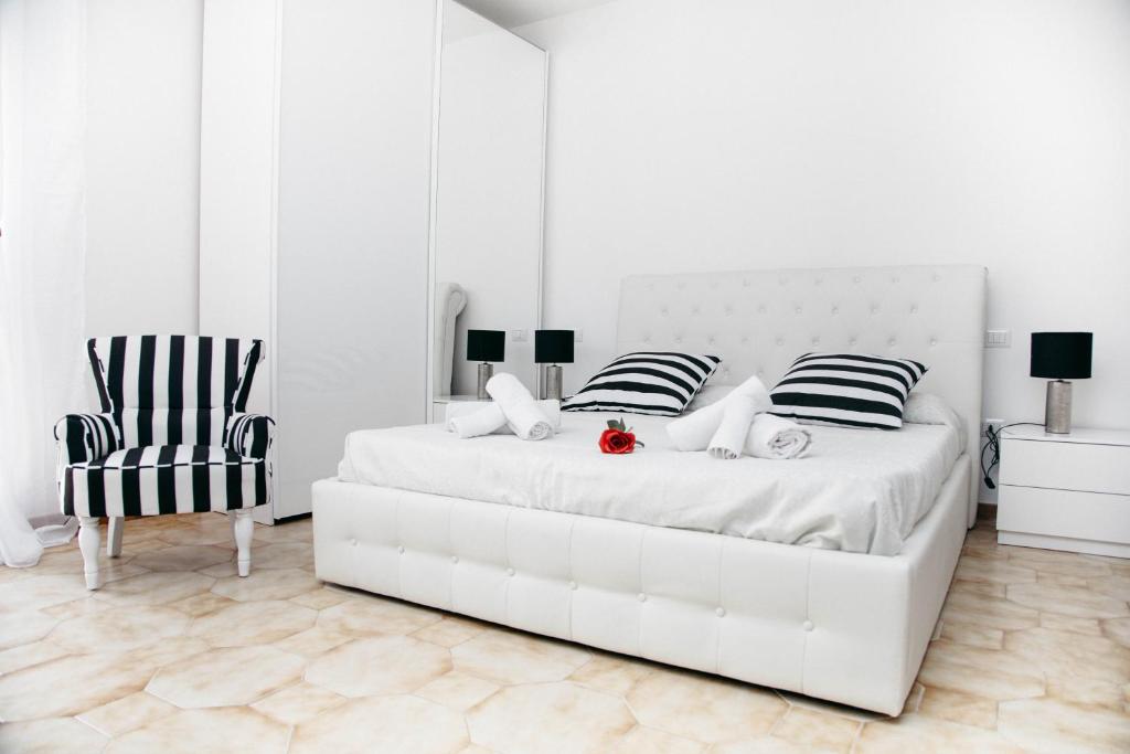 a white bedroom with a white bed and a chair at Casa Marzia Affittacamere in Alghero