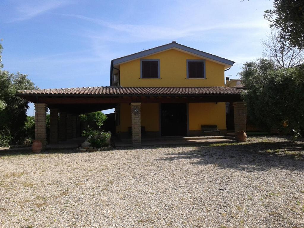 une grande maison jaune avec un toit dans l'établissement la Campagnola, à Cerveteri