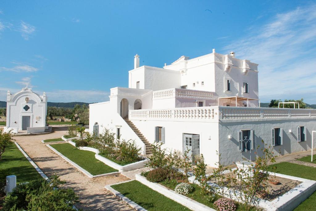 una grande casa bianca con un giardino di fronte di Masseria San Giovanni - Epoca Collection a Fasano