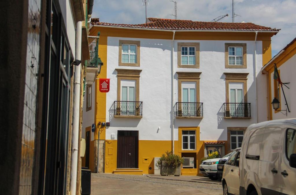 un edificio blanco y amarillo en una calle de la ciudad en Casa do Arco Portalegre en Portalegre