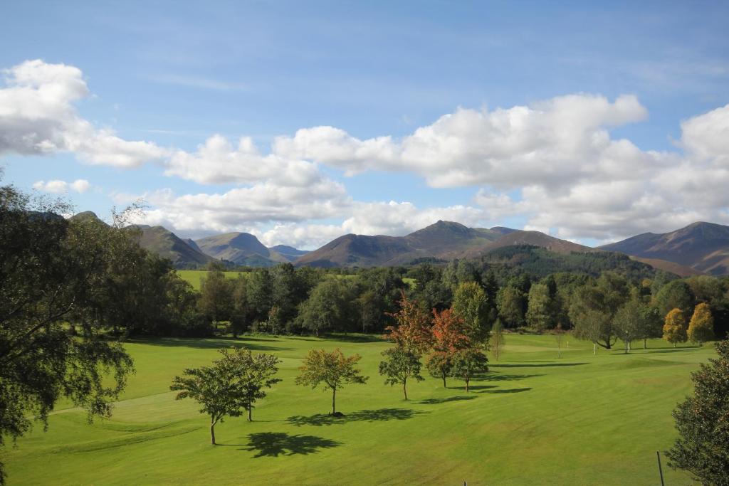 a green field with trees and mountains in the background at West View in Keswick