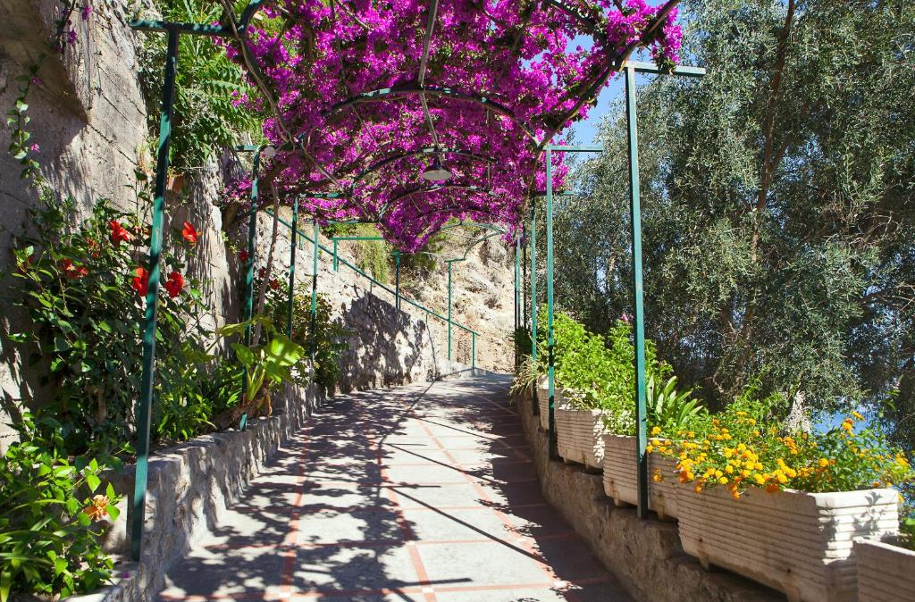 a garden with purple flowers hanging over a pathway at Hotel Pupetto in Positano