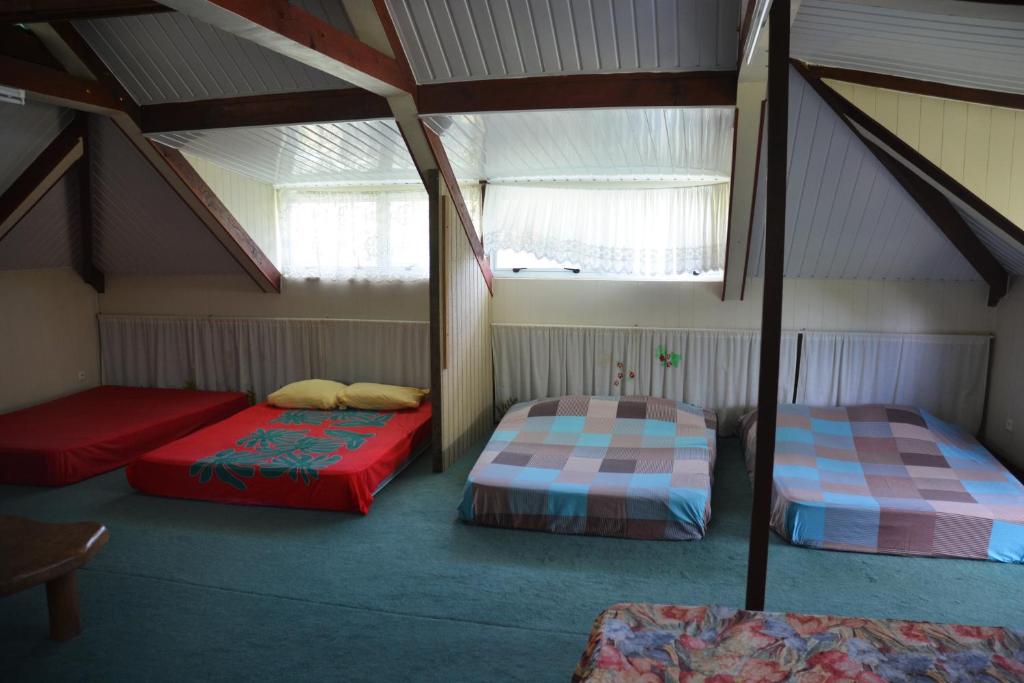 two beds in a room with two windows at Fare Maheata in Pihaena