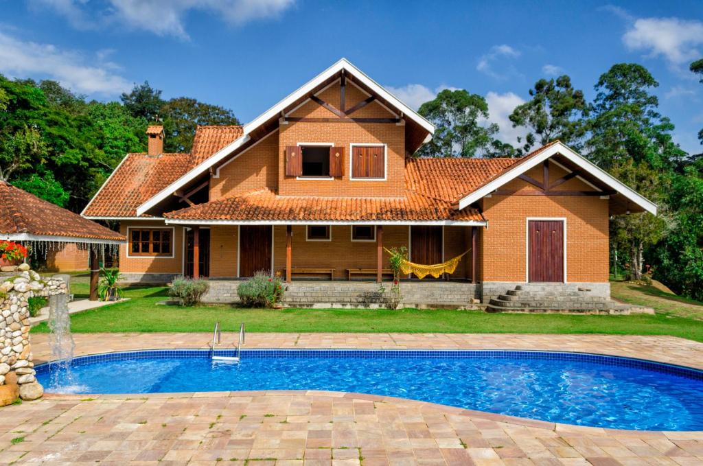 a house with a swimming pool in front of a house at Pousada Casa Da Colina in Santo Antônio do Pinhal