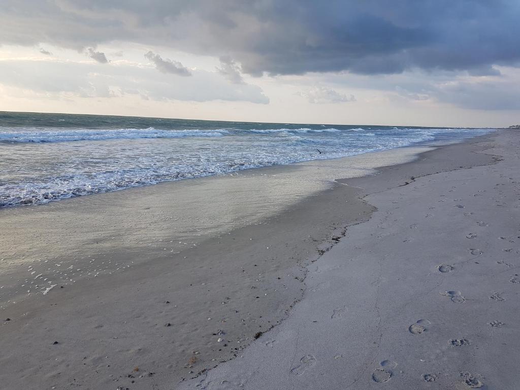 ein leerer Strand mit Fußabdrücken im Sand und im Ozean in der Unterkunft South Beach Inn - Cocoa Beach in Cocoa Beach