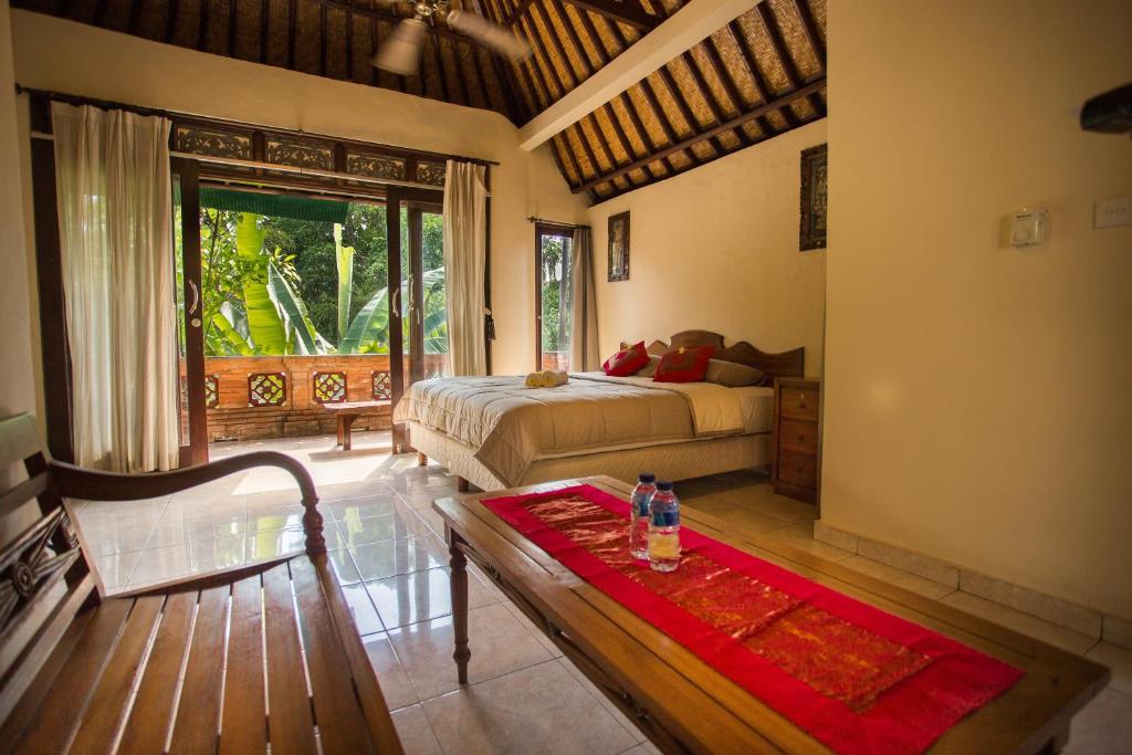 a bedroom with a bed and a table in a room at Bali Asli Lodge by EPS in Ubud