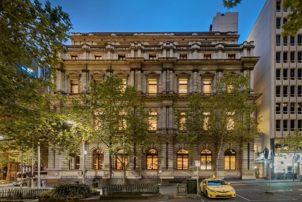 um táxi amarelo estacionado em frente a um edifício em Treasury on Collins em Melbourne