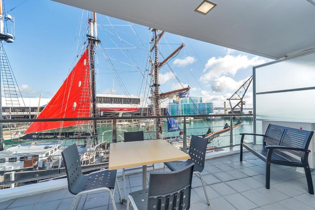 una mesa y sillas en un balcón con un barco en QV Private Airconditioned Waterfront Apartment - 423 en Auckland