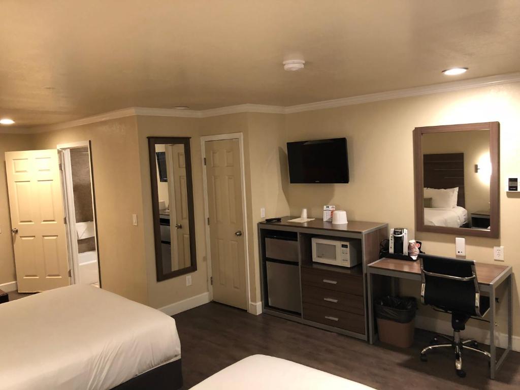 a hotel room with a bed and a desk with a computer at El Castell Motel in Monterey