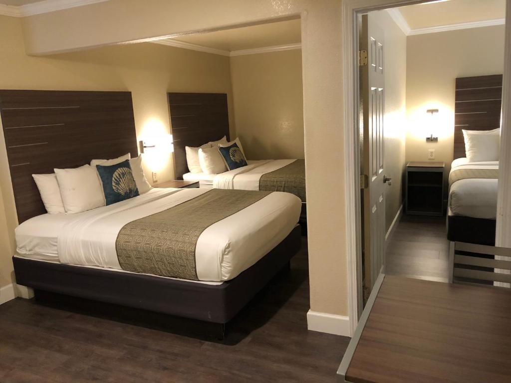 a hotel room with two beds and a mirror at El Castell Motel in Monterey