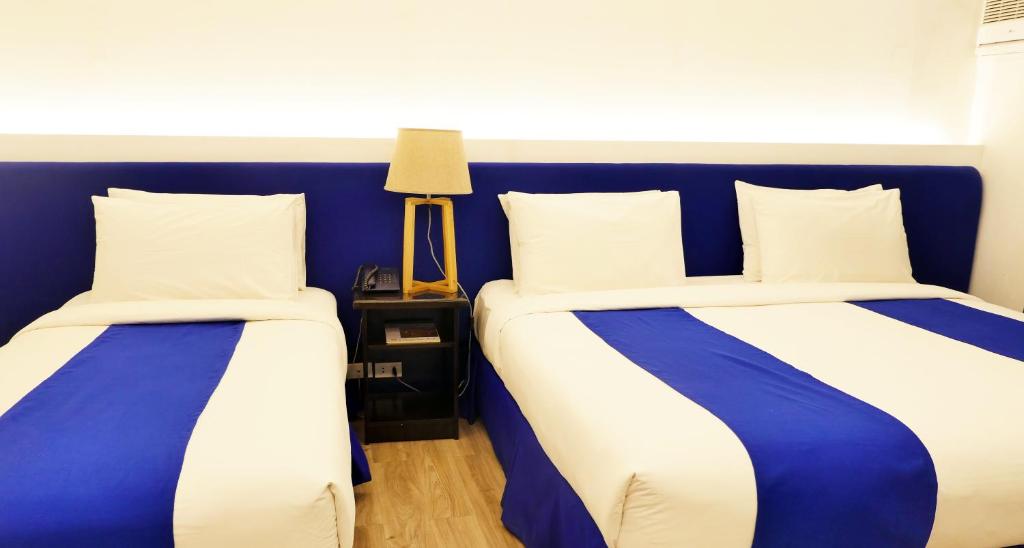 two beds in a room with blue and white at GT Hotel Jaro in Iloilo City