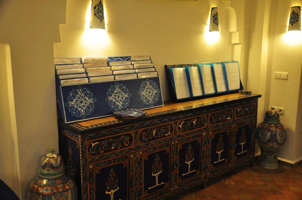 an old wooden cabinet with books on top of it at Hotel Al Alba Hammam & Restaurant in Asilah