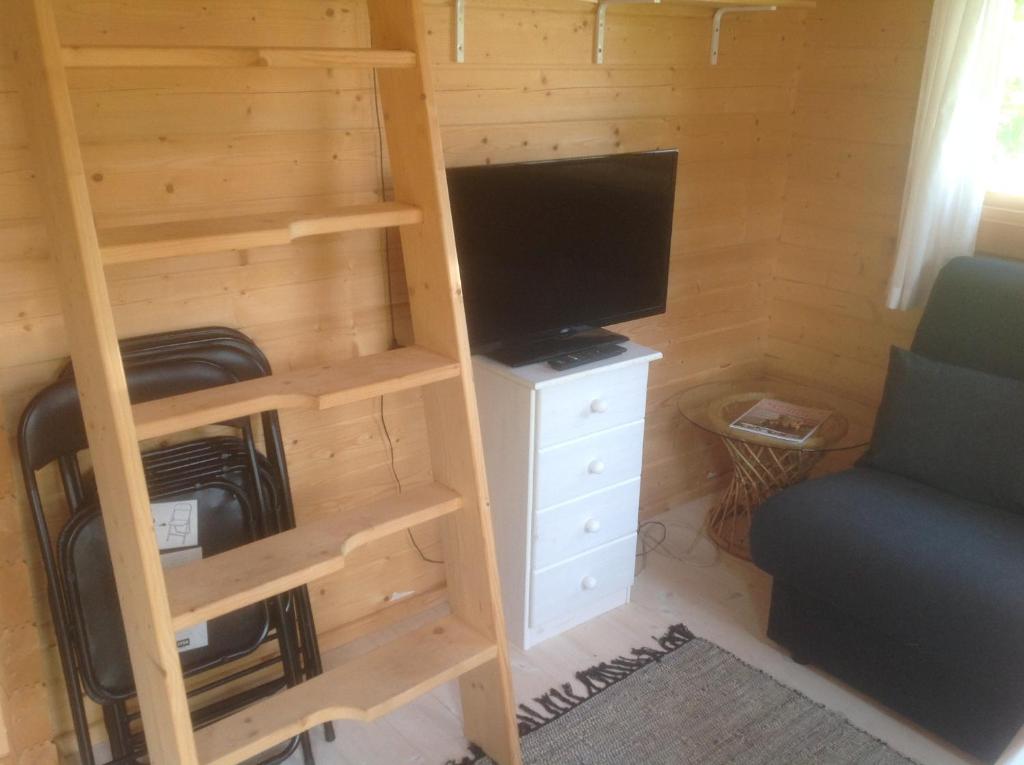 Habitación con escalera, TV y silla en Hjemstavnsgårdens Camping & Cottages, en Glamsbjerg