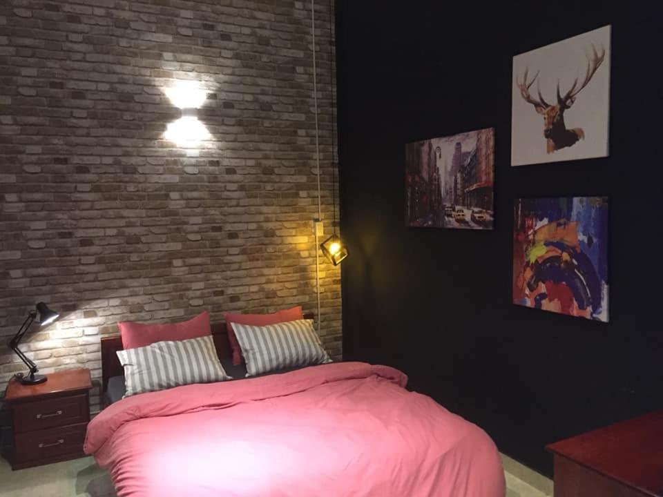 a bedroom with a pink bed and a brick wall at 08 Homestay in Can Tho